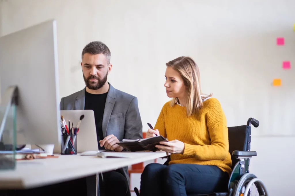 Mann und Frau im Rollstuhl am Schreibtisch